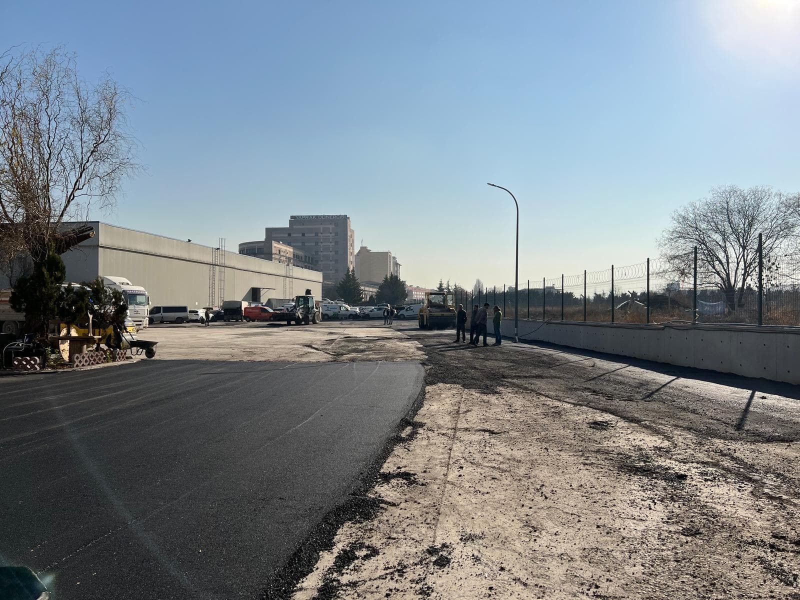 Endüstriyel tesis otoparkında yeni asfalt şeridi ve saha ekipmanı